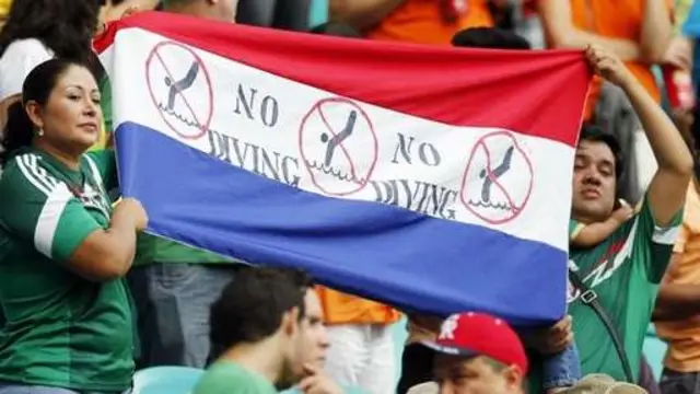 Các cổ động viên căng biểu ngữ đề nghị cầu thủ không ngã ăn vạ câu phạt đền.