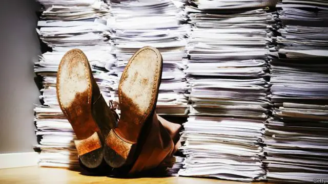 Trabajador enterrado bajo torres de papel