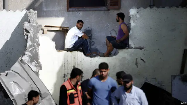 Palestinos en los restos de un edificio atacado por Israel en Jan Yunis