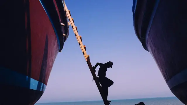 قشم میں خشک گودی میں موجود ایک کارکن۔ اب یہاں زیادہ تر کشتیاں لکڑی کی بجائے فائبرگلاس سے بنائی جاتی ہیں لیکن آج بھی کشتی سازی اور ماہی گیری اس جزیرے پر روزگار کے بنیادی ذرائع ہیں۔