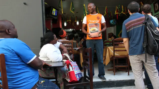 Victor Macaia (katikati) na mkewe Melanito Biyouha, wanatoka nchini Cameroon. Walifungua mgahawa wao wa chakula cha kiafrika mjini Sao Paulo miaka sita iliyopita. "mwanzoni asilimia 80 ya wateja wetu walikuwa waafrika, lakini sasa asilimia 90 ni wageni na wenyeji wa-Brazil. Chakula chetu chote ni cha kiafrika,'' alisema mwanamume huyo. 