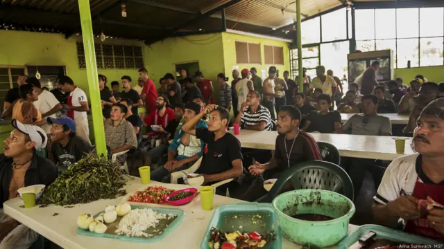Migrantes comen y ven partido de fútbol