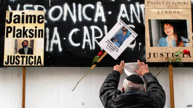 Hombre coloca de espaldas frente a carteles con nombres de víctimas del atentado