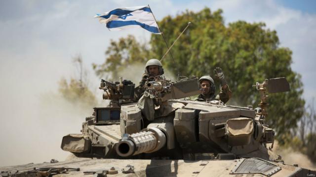 En la imagen, un soldado israelí saluda mientras conduce un tanque Merkava en la frontera con Gaza. Crédito: AFP/Getty.