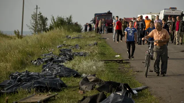La gente pasa junto a los restos de las víctimas en sacos plásticos