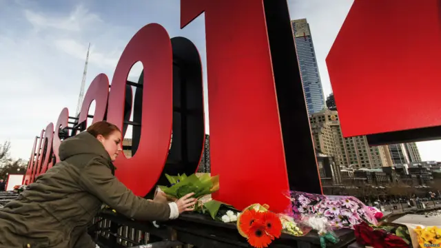 澳大利亚墨尔本， 国际艾滋病大会标志下，一名妇女献上鲜花。