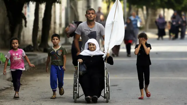 زنی که در حال فرار از محله شجاعیه است پرچم سفید به دست گرفته