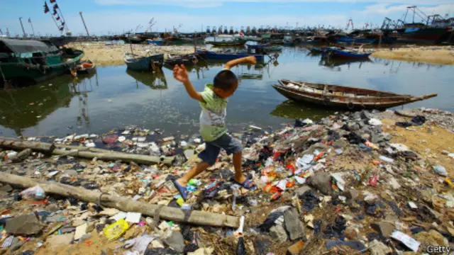 Niño salta sobre basura en la playa de Anquan, al sur de China.