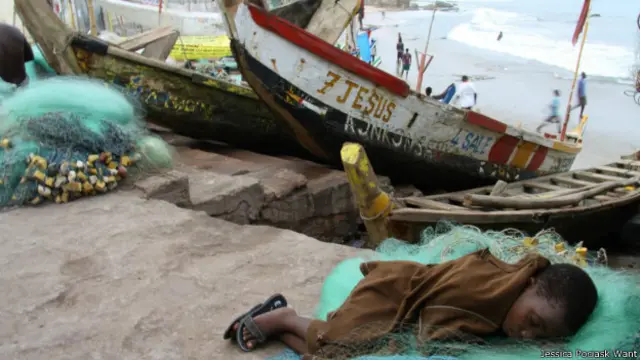 Niño descansando junto a un bote de pesca