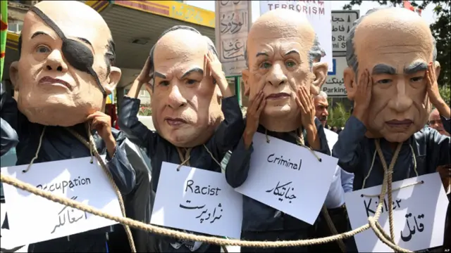 تعدادی از راهپیمایان در تهران، ماسک چهار چهره اسرائیلی را به چهره دارند. ماسک دومی از چپ، چهره بنیامین نتانیاهو و ماسک نفر سمت چپ، چهره موشه دایان، وزیر سابق امور خارجه اسرائیل است