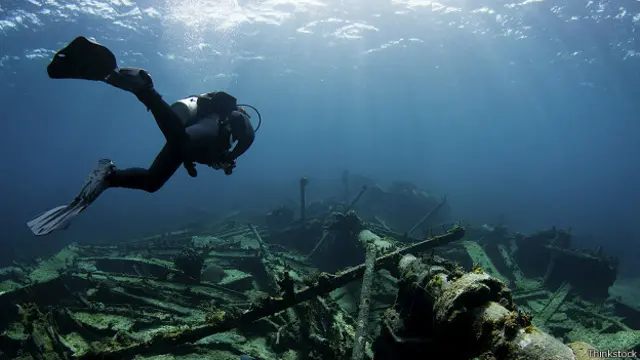 Ныряльщик плывет под водой над останками корабля