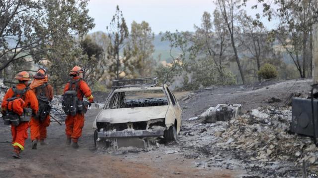 Bomberos caminan a un lado de un carro destruido por el incendio forestal conocido como “El incendio de arena” ("The Sand Fire"), en el Condado de Amador, en el norte de Plymouth, norte de California. EPA 