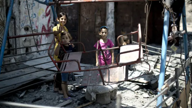 غزہ کے علاقے شجائیہ میں بچے ایک بمباری میں ٹوٹ جانے والے جھولے کے قریب کھڑے ہیں۔