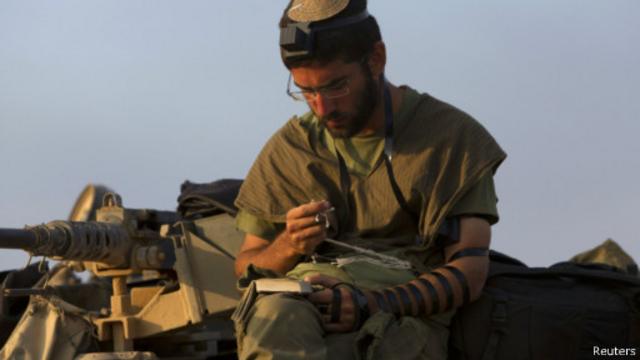 جندي إسرائيل يقرأ التوراة على متن دبابة قرب حدود غزة. ويطالب نتنياهو الشعب الإسرائيلي بالوقوف وراء الجيش في حرب قال إنها ستطول مع حماس.