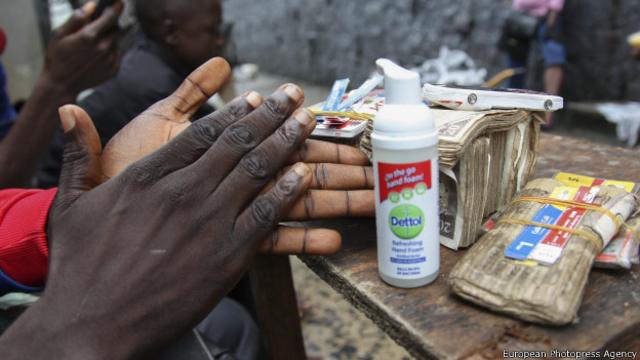 Un hombre se limpia las manos en Liberia antes de cambiar dinero a un cliente.