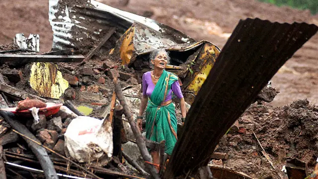 मलबे में अपना सामान तलाशती एक महिला