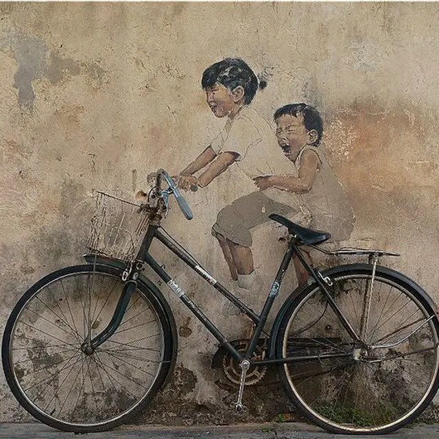 ایلیکس انمین: ’ملیشیا کی ایک گلی میں دیوار پر دو بچوں کی تصویر بنائی گئی ہے جو اصل سائیکل پر سواری کا لطف لے رہے ہیں۔‘