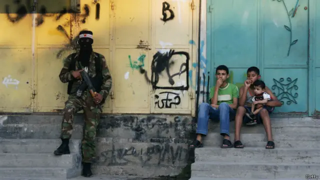 Niños en la Franja de Gaza con un militante armado