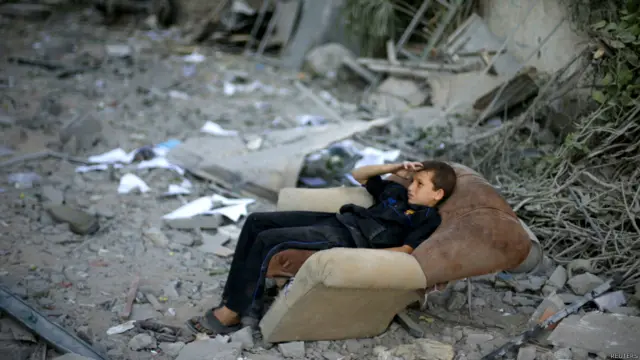 این پسر در حیاط خانه‌شان که در حمله هوایی اسرائیل ویران شده نشسته است