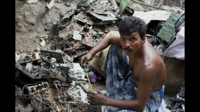 हामिद नस्कर इलेक्ट्रॉनिक कचरे की ढेर पर बैठे हुए हैं.