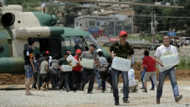 雲南魯甸龍頭山鎮災場志願者幫助從軍方直升機卸下瓶裝水（新華社圖片5/8/2014）