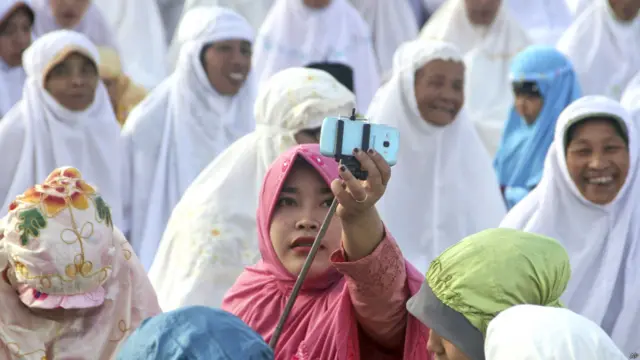 انڈونیشیا کے شہر یوگیاکارتا میں ایک خاتون عید الفطر کی نماز پر سیلفی لیتے ہوئے۔