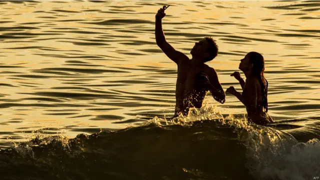 برازیل کے شہر ریو ڈی جنیرو میں ایک جوڑا سمندر کی لہروں میں سیلفی لے رہے ہیں۔ 