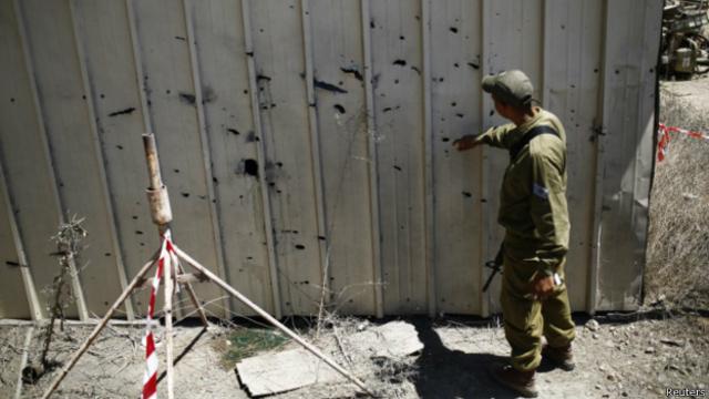 Израильский солдат осматривает следы от ракетного обстрела 