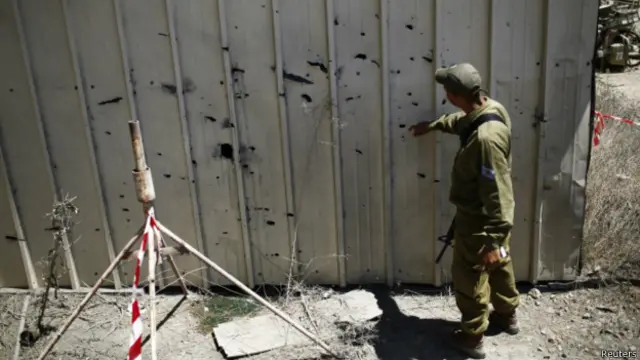 Израильский солдат осматривает следы от ракетного обстрела 
