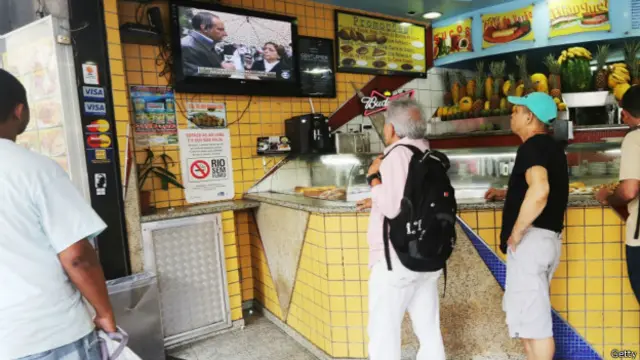Brasileños miran un informativo de TV en un bar.