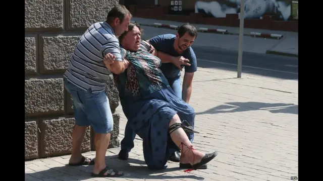 Прохожие помогают раненой женщине