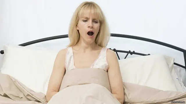 Женщина зевает в постели