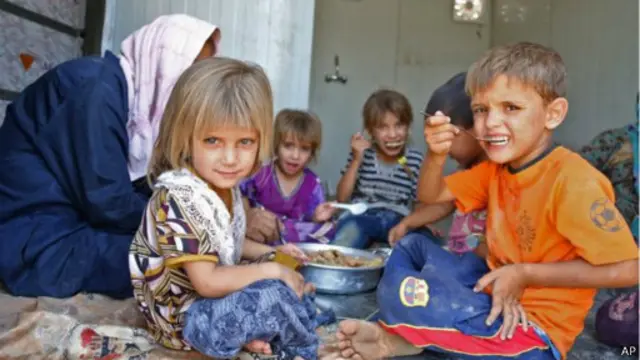 لاجئون شيعة يتناولون الطعام في الموصل