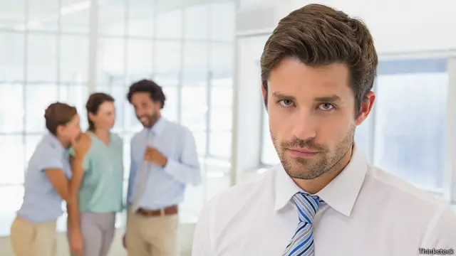 Бизнесмен и его коллеги, шепчущиеся на заднем плане