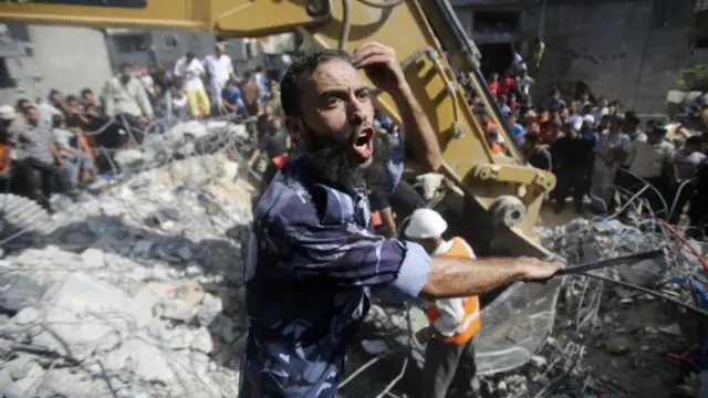 شرطي فلسطيني يعبر عن غضبه بينما يبحث عمال الإنقاذ عن الضحايا تحت أنقاض منزل دمر تماما في القصف.