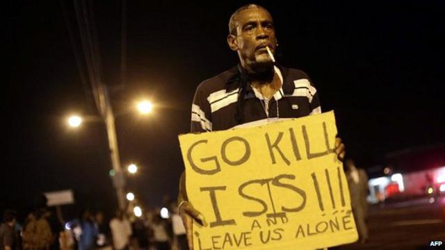 متظاهر يحمل لافتة يقول فيها للشرطة "اذهبوا واقتلوا داعش واتركونا وشأننا."
