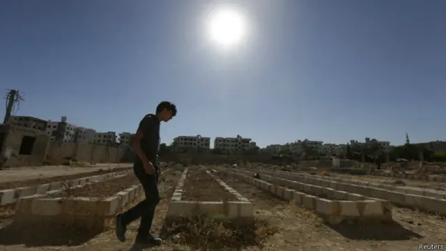 Joven camina entre tumbas masivas en çZamalka, Siria.