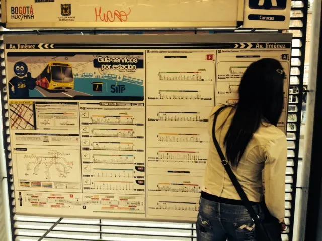 Mujer estudiando el mapa de rutas del Transmilenio.