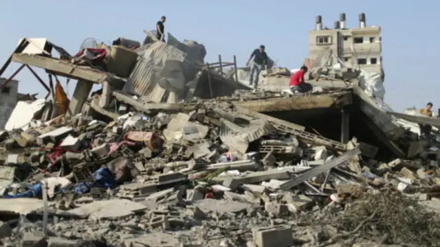 فلسطينيون يبحثون عن بعض ممتلكاتهم وسط حطام منزلهم الذي دمر في غارة اسرائيلية