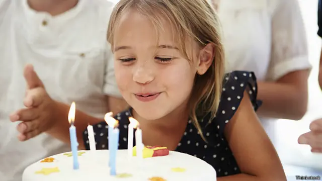 Девочка задувает свечки на торте