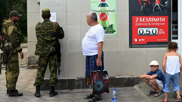 Жители Новоазовска (в 50 км от Мариуполя) наблюдают за сепаратистами, наклеивающими что-то на стену