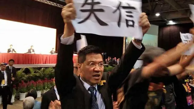 泛民主派议员范国威在李飞香港政改简介会上展示抗议标语（BBC中文网图片1/9/2014）