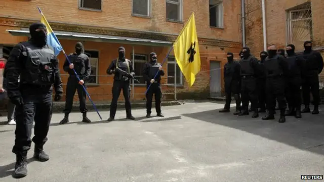 Unos combatientes del batallón Azov portan una bandera con el simbolo "Wolfsangel", asociado con los neo nazis.