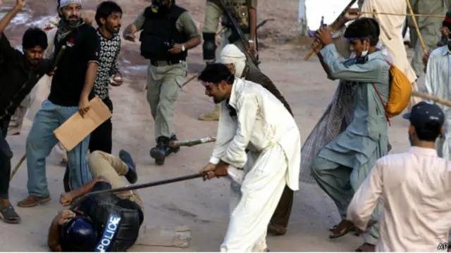 محتج يضرب رجل شرطة بعصاة