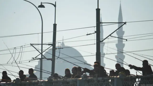 Hüsnü Sarıova: Güneşli bir Şubat günü. Dalga sesleri, martı çığlıkları, seyyar satıcı bağrışmaları, dizel motor homurtuları ve vapur kornaları arasında işte İstanbul.