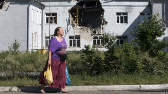 Местная жительница на фоне поврежденной школы в городе Лисичанск, Луганская область