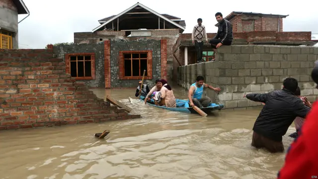 श्रीनगर के बाहरी इलाक़े में नाव में बैठककर सुरक्षित स्थान की ओर जाता एक परिवार.