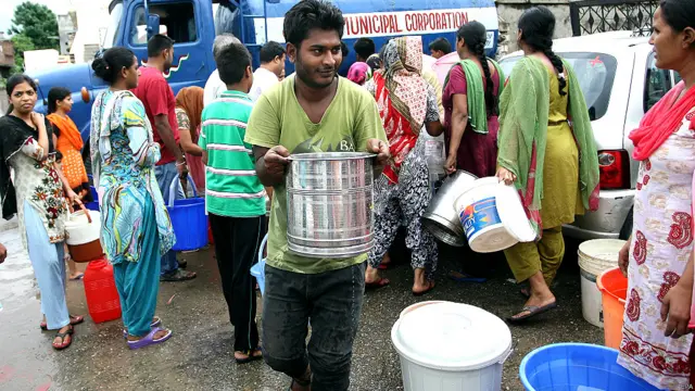 जम्मू में टैंकर से भरकर पीने का पानी ले जाता एक व्यक्ति.