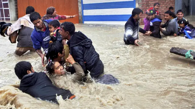 श्रीनगर में पानी के तेज़ बहाव में बचने की कोशिश करते लोग. 