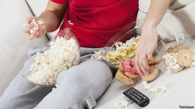 Homem come em frente à TV | Crédito: Thinkstock